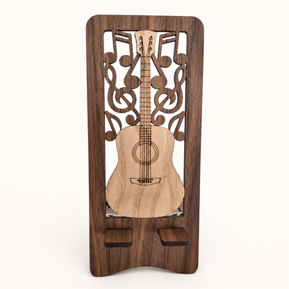 A wooden guitar-shaped phone holder with a dark brown walnut wood frame, laser-cut musical notes and guitar design in the center, showing the two tabs that the phone sits on. Shown on a plain light background.