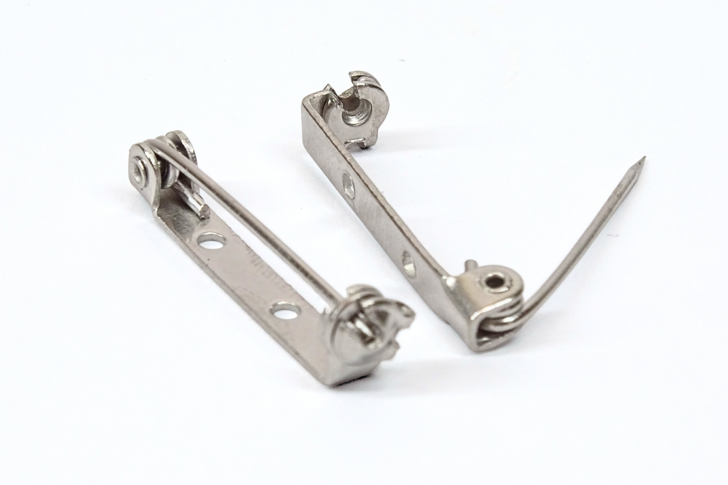 Two brooch pins on a white background. One pin open the closed