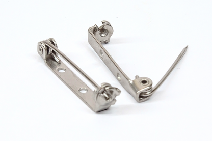 Two brooch pins on a white background. One pin open the closed