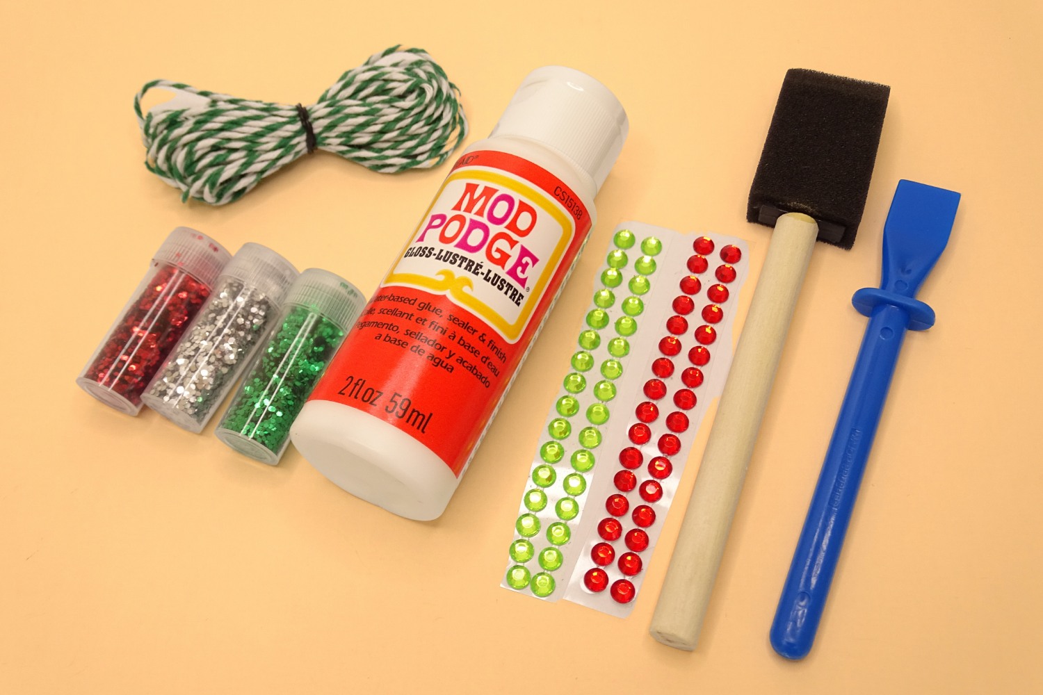 Coloured glitter and sparkles, foam brush and glue spreader also small bottle of mod podge that are included in the kit