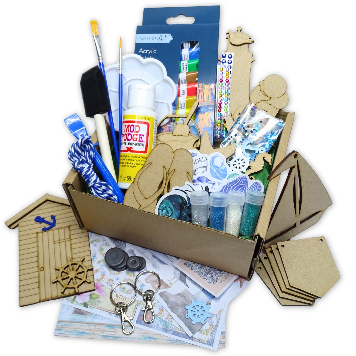 Craft supplies including paintbrushes, acrylic paint, and decorative items in a cardboard box on a white background.