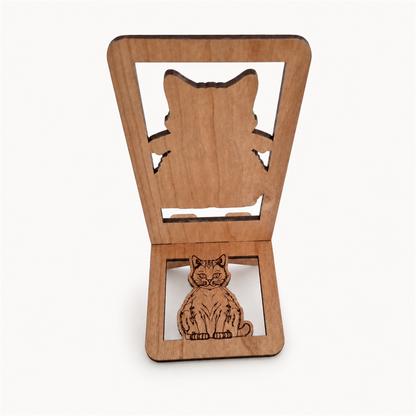 Back of wooden phone stand, featuring a large cat silhouette cutout on the upper panel and a smaller laser-engraved cat figure on the lower panel, shown on a light gray background.