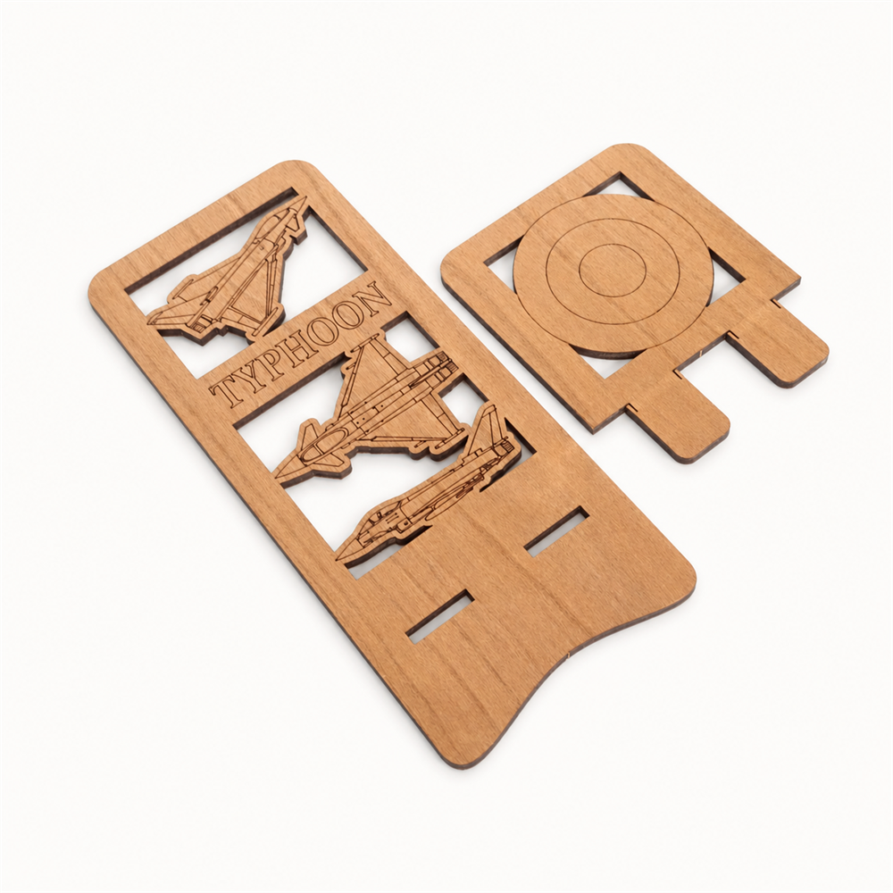 Two parts of a wooden phone stand with engraved jet aircraft designs and the word 'TYPHOON' laying flat on a plain white background.