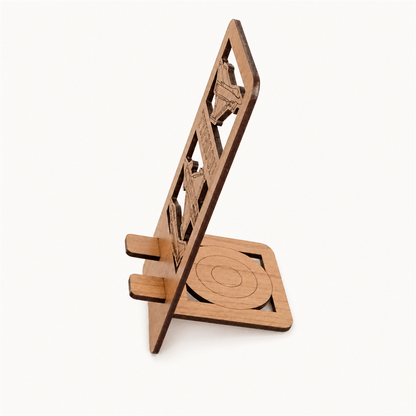 Side view of a wooden phone stand with a laser-cut design, shown on a plain light background.
