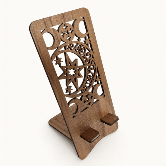 A wooden phone stand with intricate laser-cut celestial patterns of stars, moons, and planets, shown on a clean off-white background.