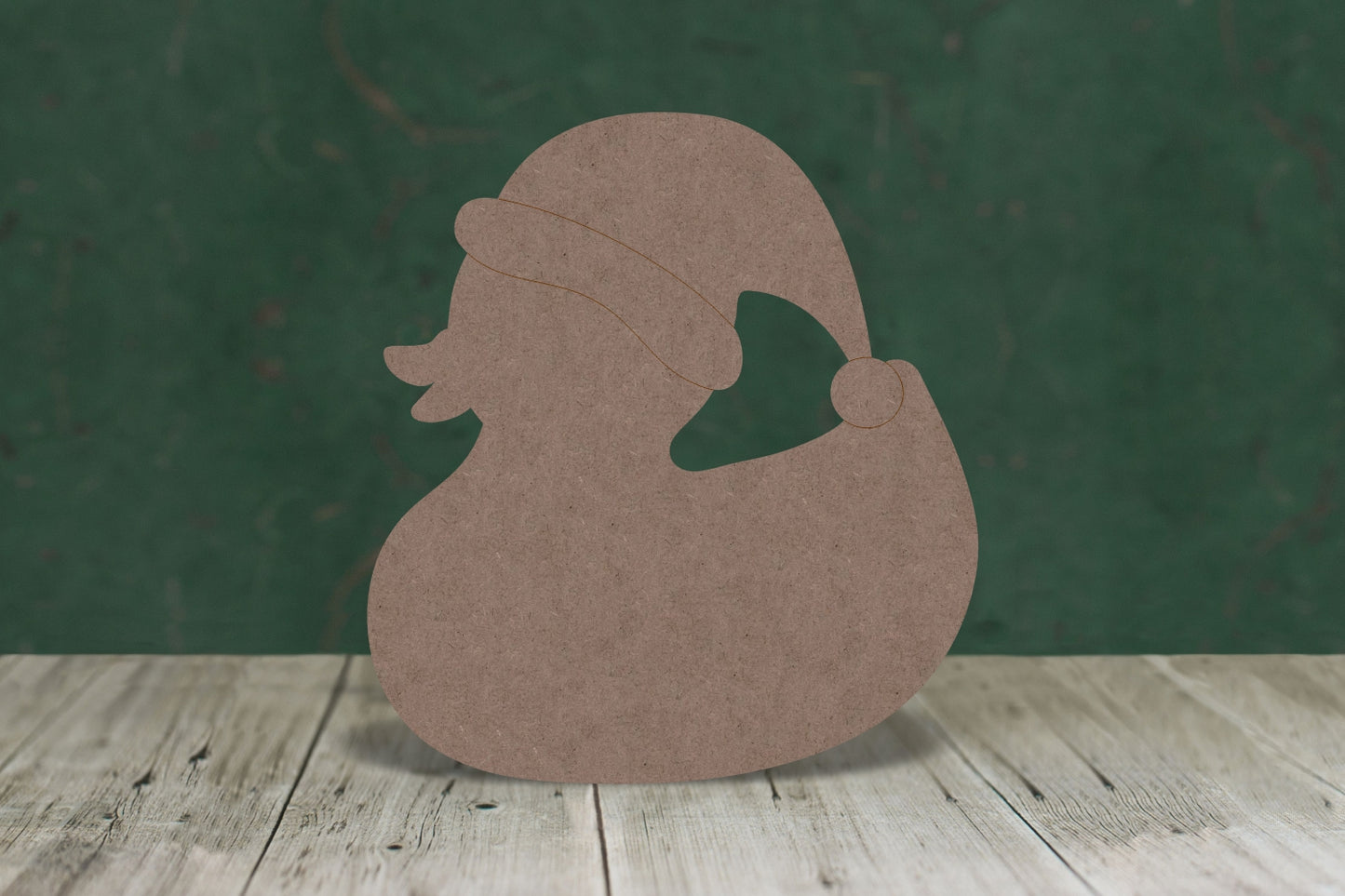 2mm MDF craft blank in the shape of a duck wearing a Santa hat on a wooden table and a green background.