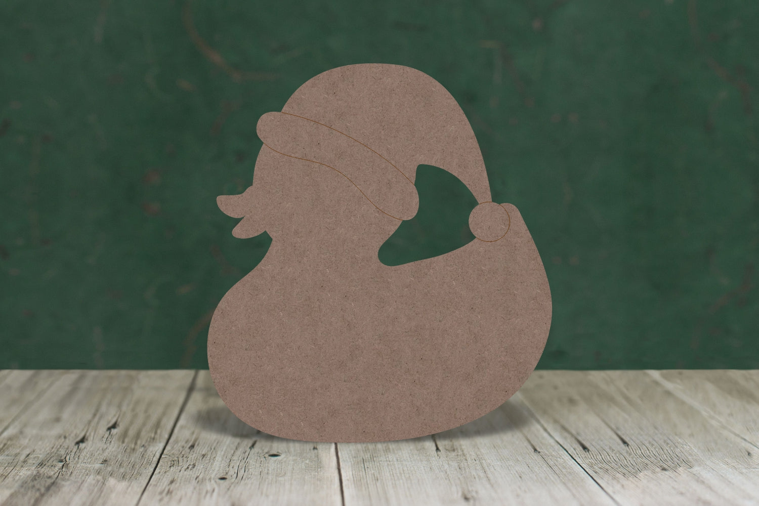 2mm MDF craft blank in the shape of a duck wearing a Santa hat on a wooden table and a green background.
